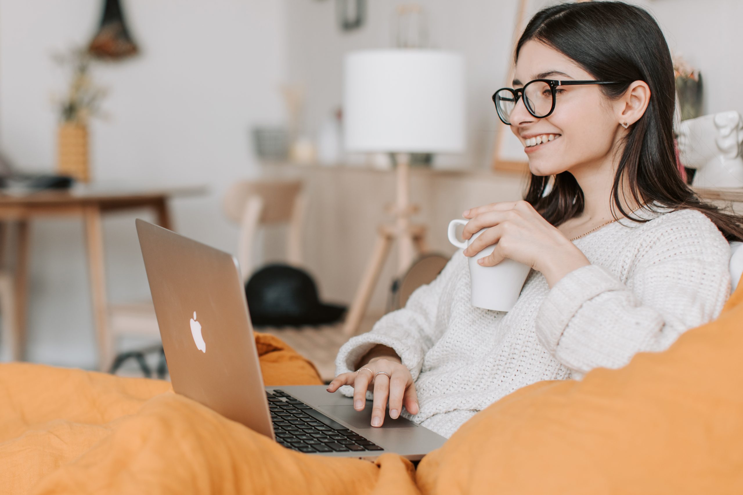 woman smiling and using her laptop holding coffee
